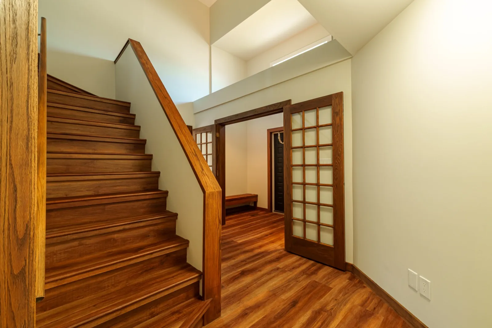 Oak staircase and handrail leading up, with glazed French doors opening to an entry beyond