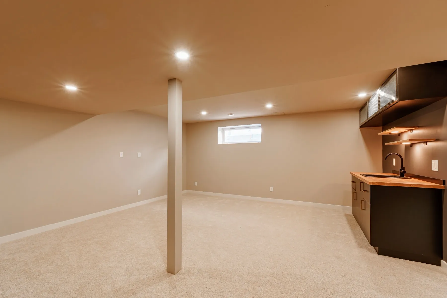 The open rec room, carpeted and pot-lit, with the wet bar along one wall