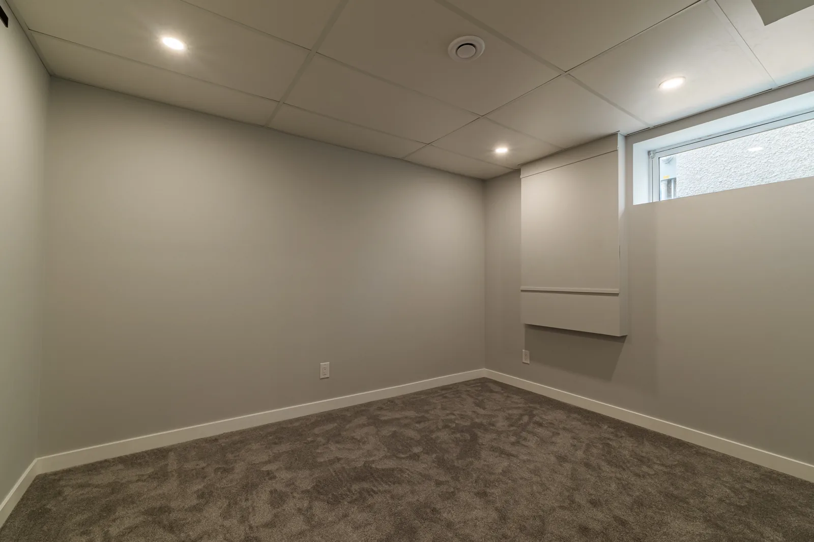 Finished basement rec room, carpet wall to wall under a pot-lit tile ceiling