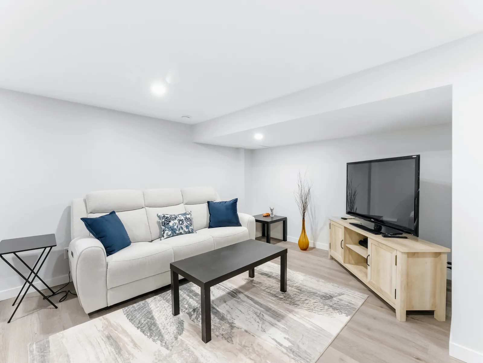 The lower level from the stair end, blond vinyl plank running the length of the floor