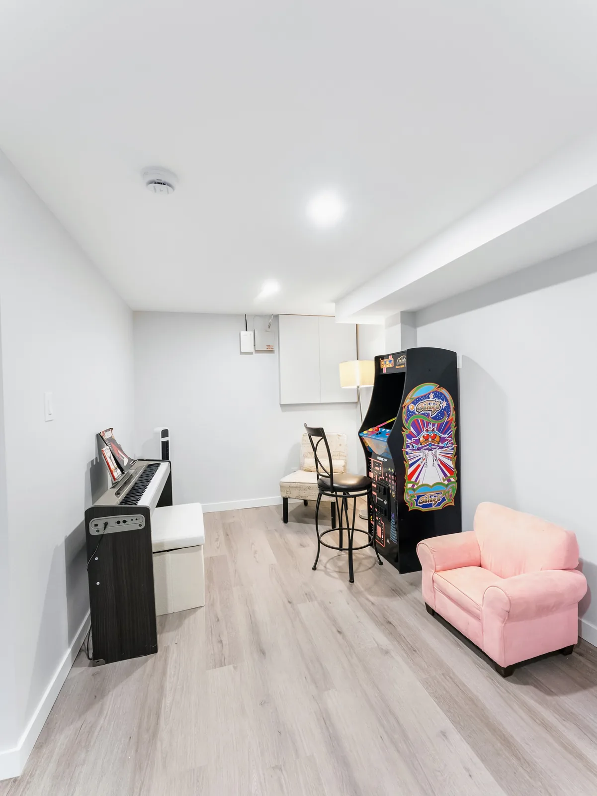 Arcade cabinet and bar stools set against the white wall