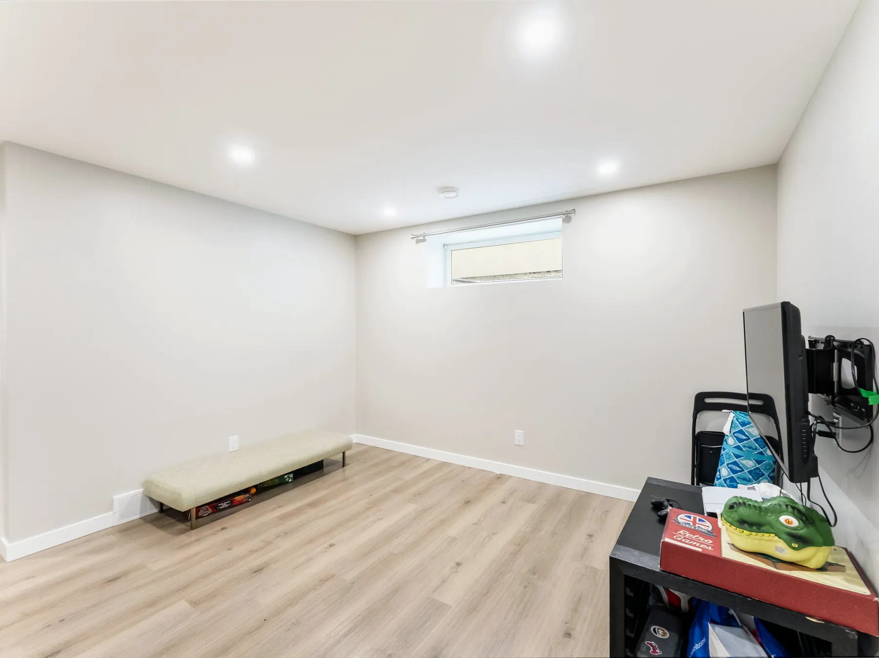 Open basement rec room with vinyl plank floor and an egress window