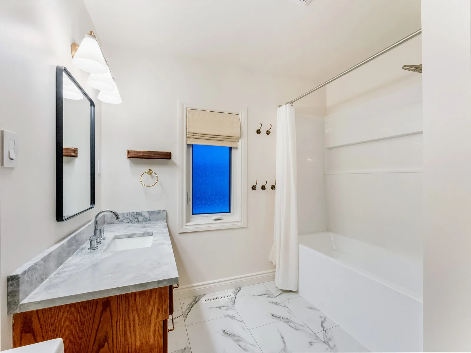 The vanity run from the tub end, marble-look tile laid across the floor