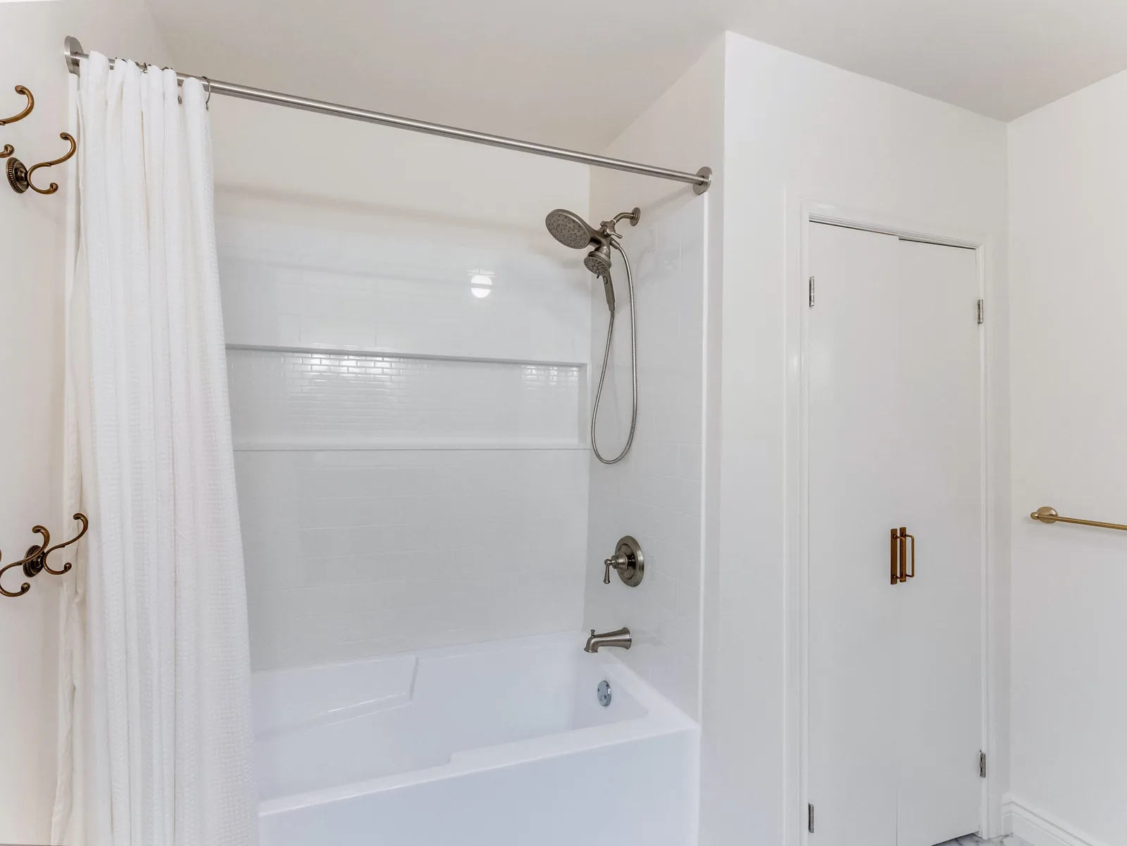 White tub-shower with a curtain rail and chrome fittings