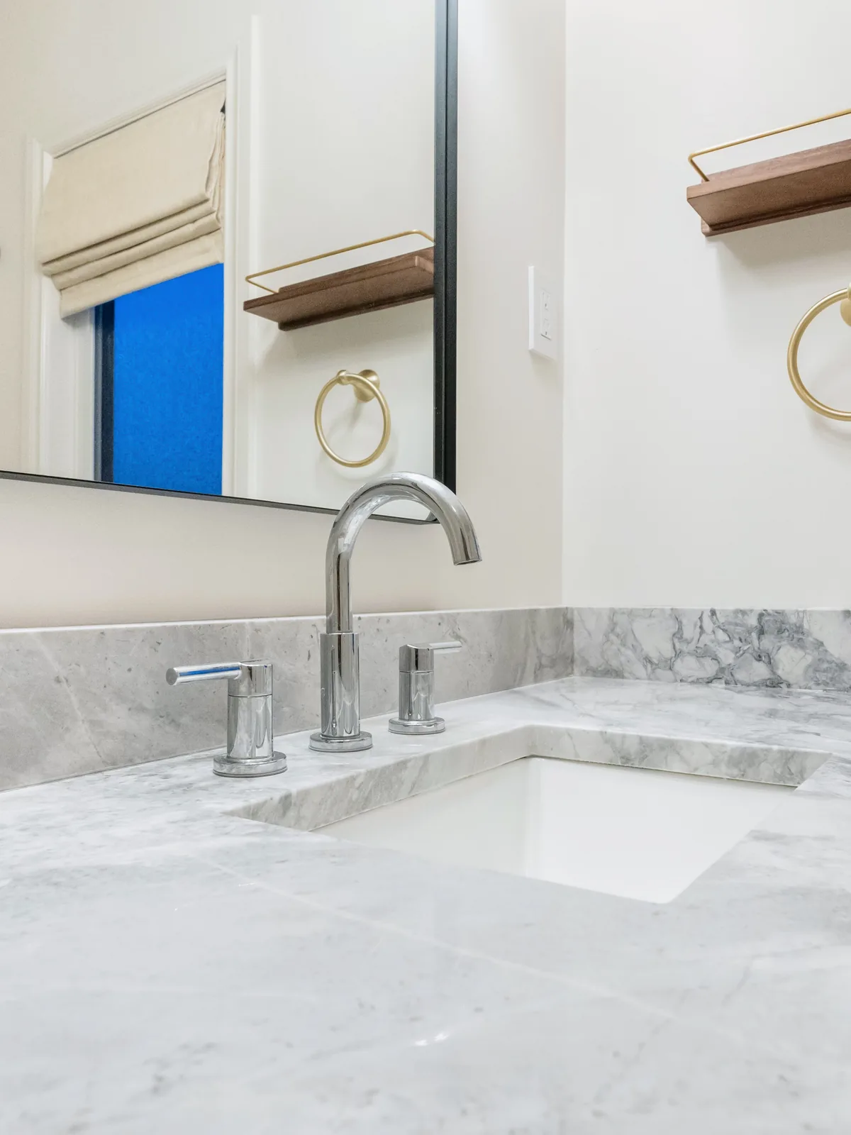 Chrome widespread tap on the marble-veined quartz, window reflected in the mirror