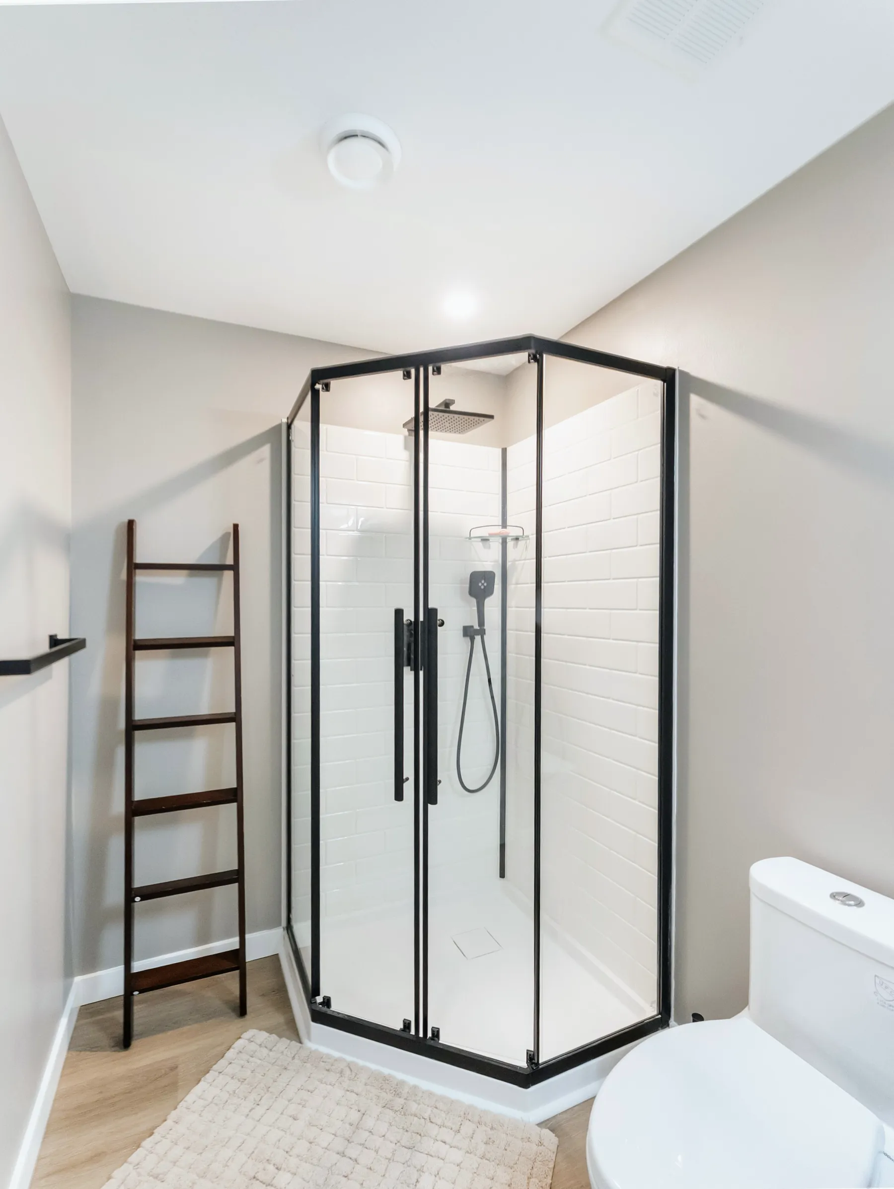 Framed glass shower and ladder towel rail in a finished basement bathroom
