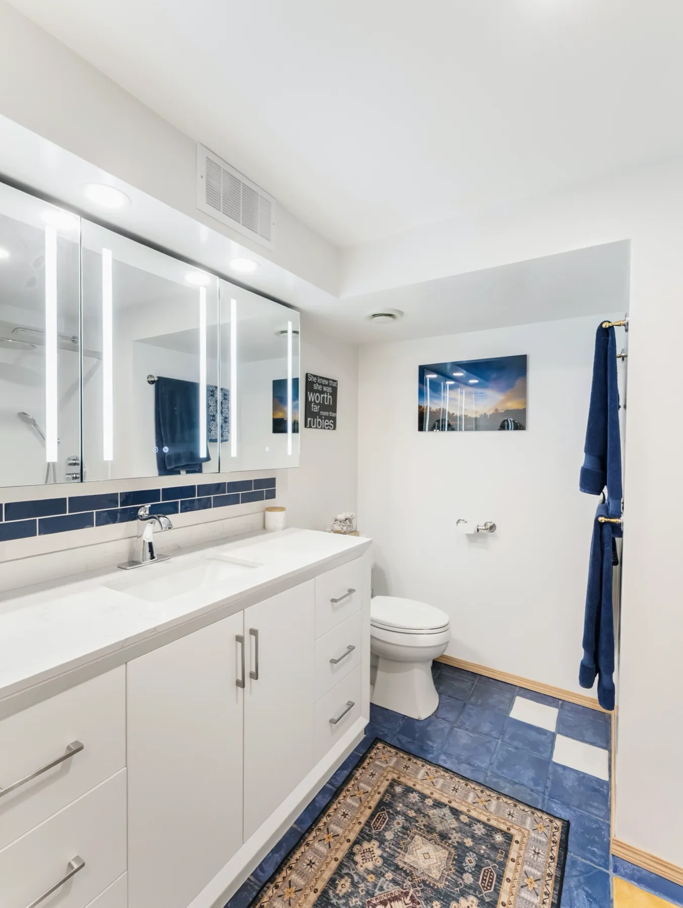 The vanity and toilet from the doorway, patterned floor tile underfoot