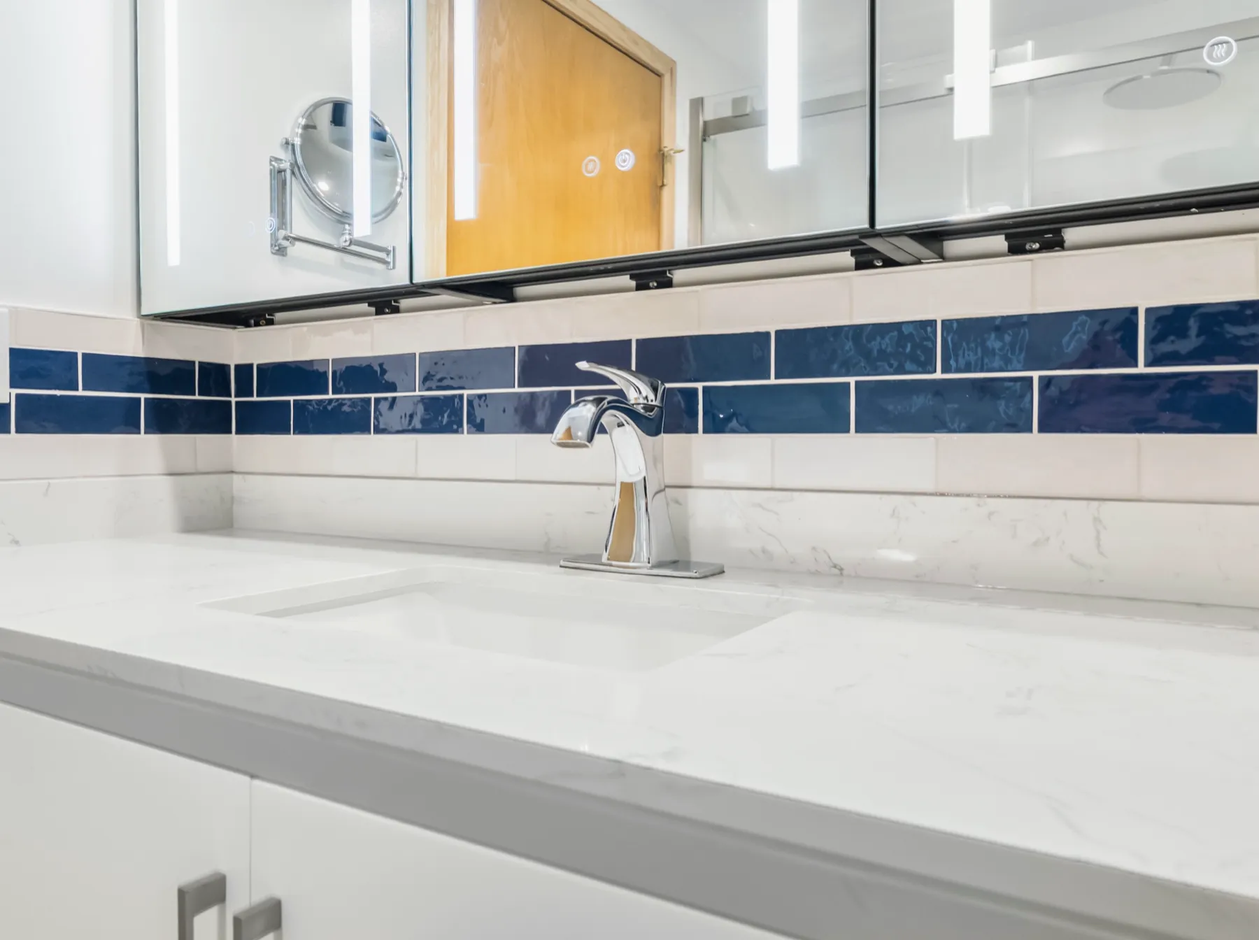 The quartz counter and tap against the cobalt tile band