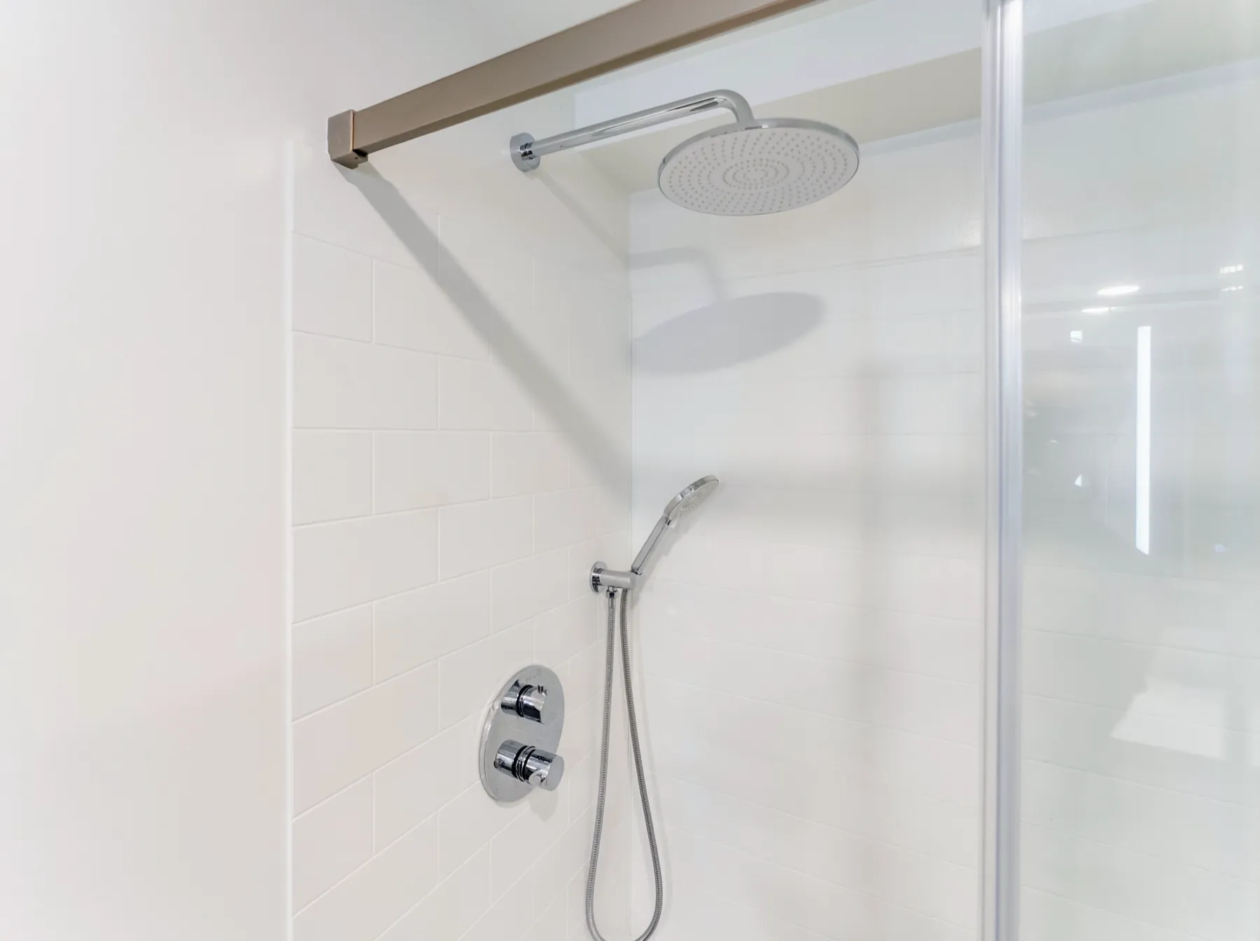Inside the shower, rain head and handset on the tiled wall