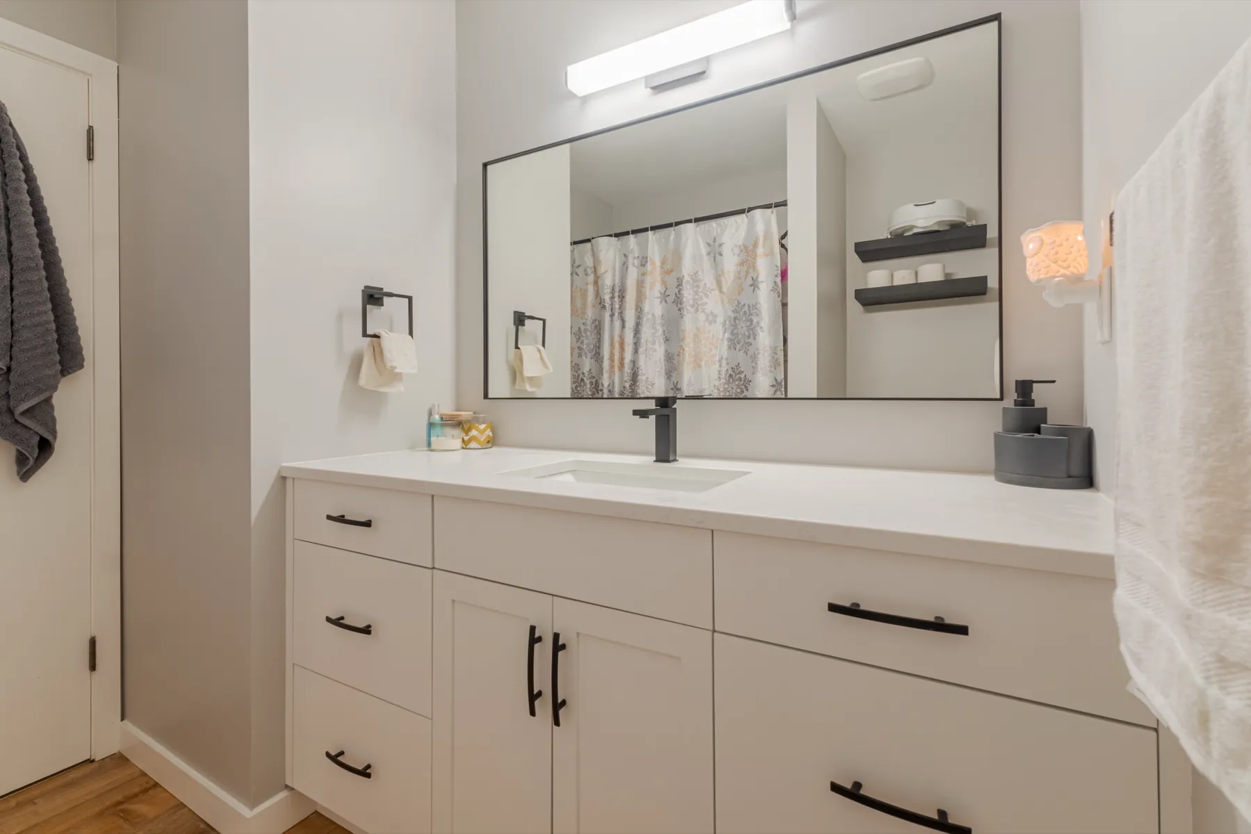 Bathroom vanity under a wide framed mirror
