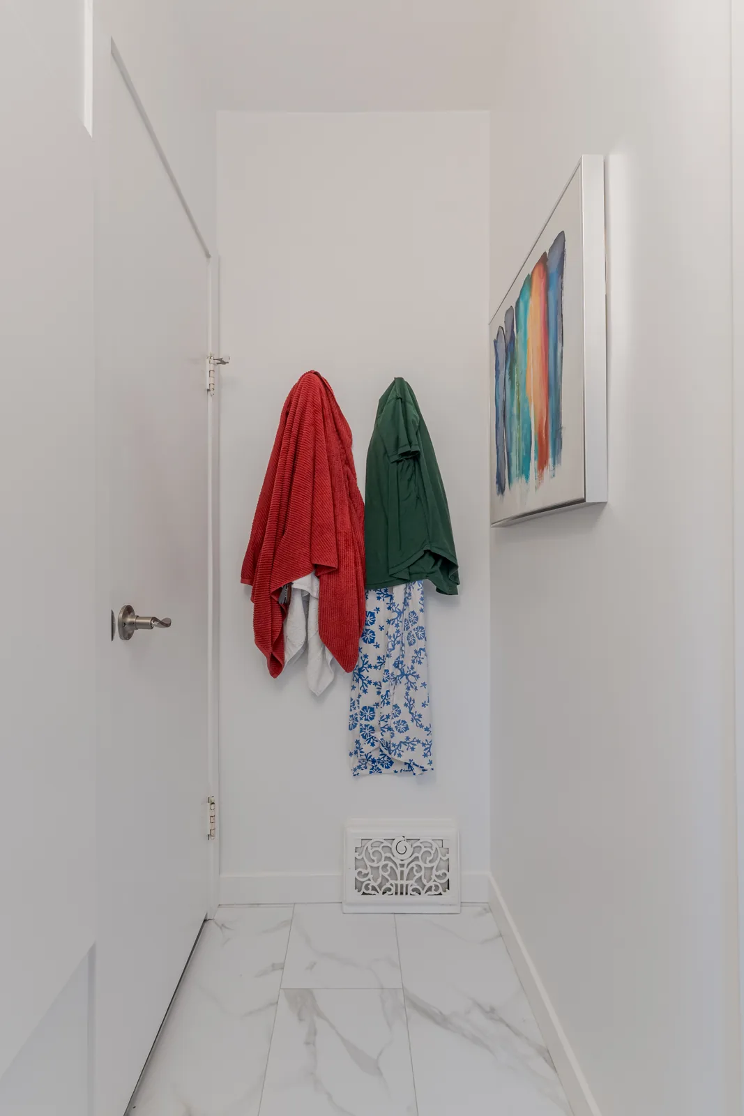 Hooks and towels on the back of the door, tile floor below