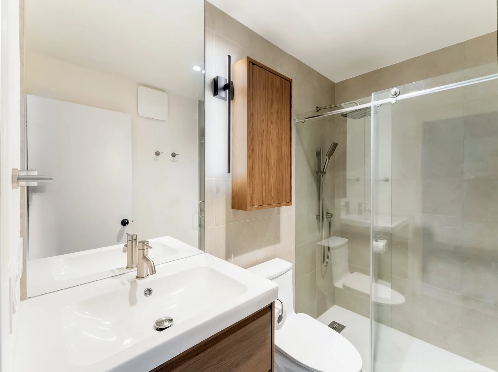 Bathroom with a wall-hung wood-front vanity, a wide basin and a sliding glass shower alongside