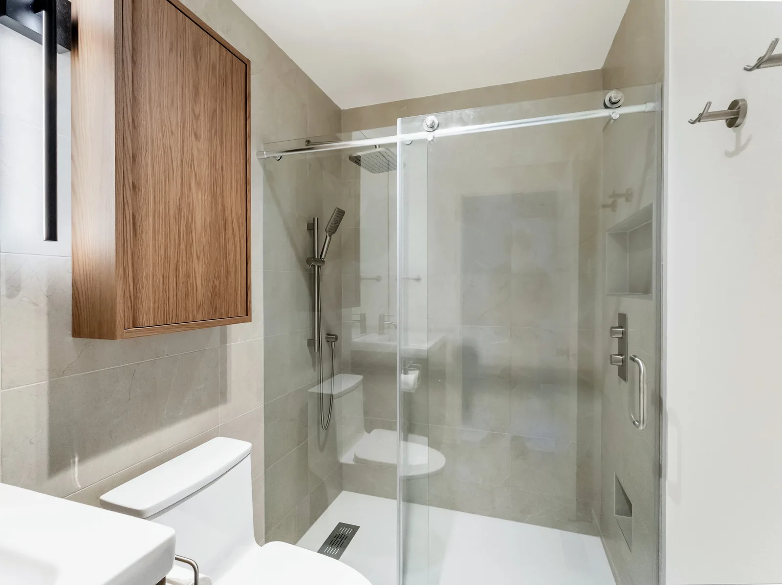 The shower run from the doorway, glass slider open to a stone-look tiled surround