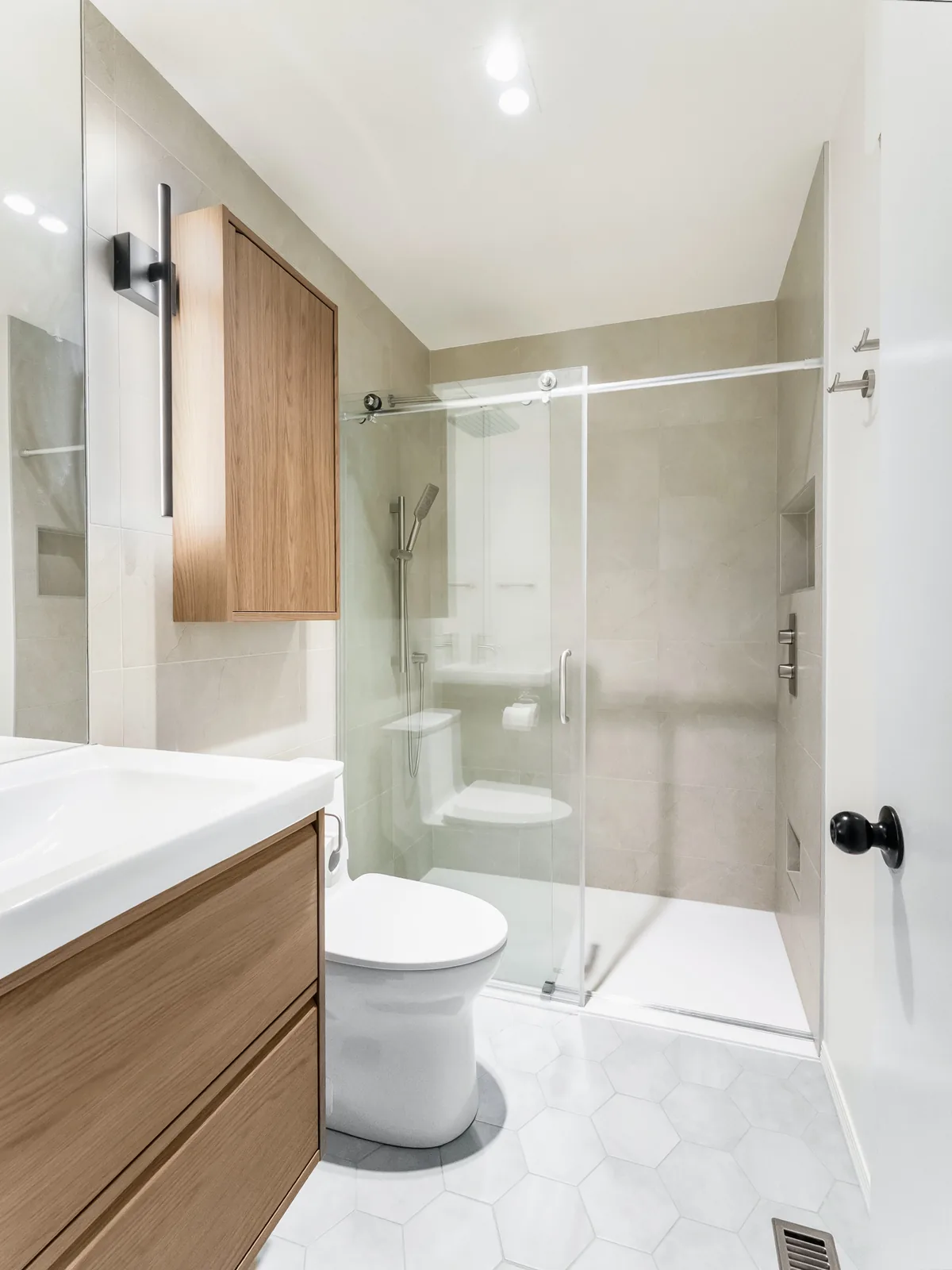 The finished bathroom under its sloped ceiling, hex tile running to the shower