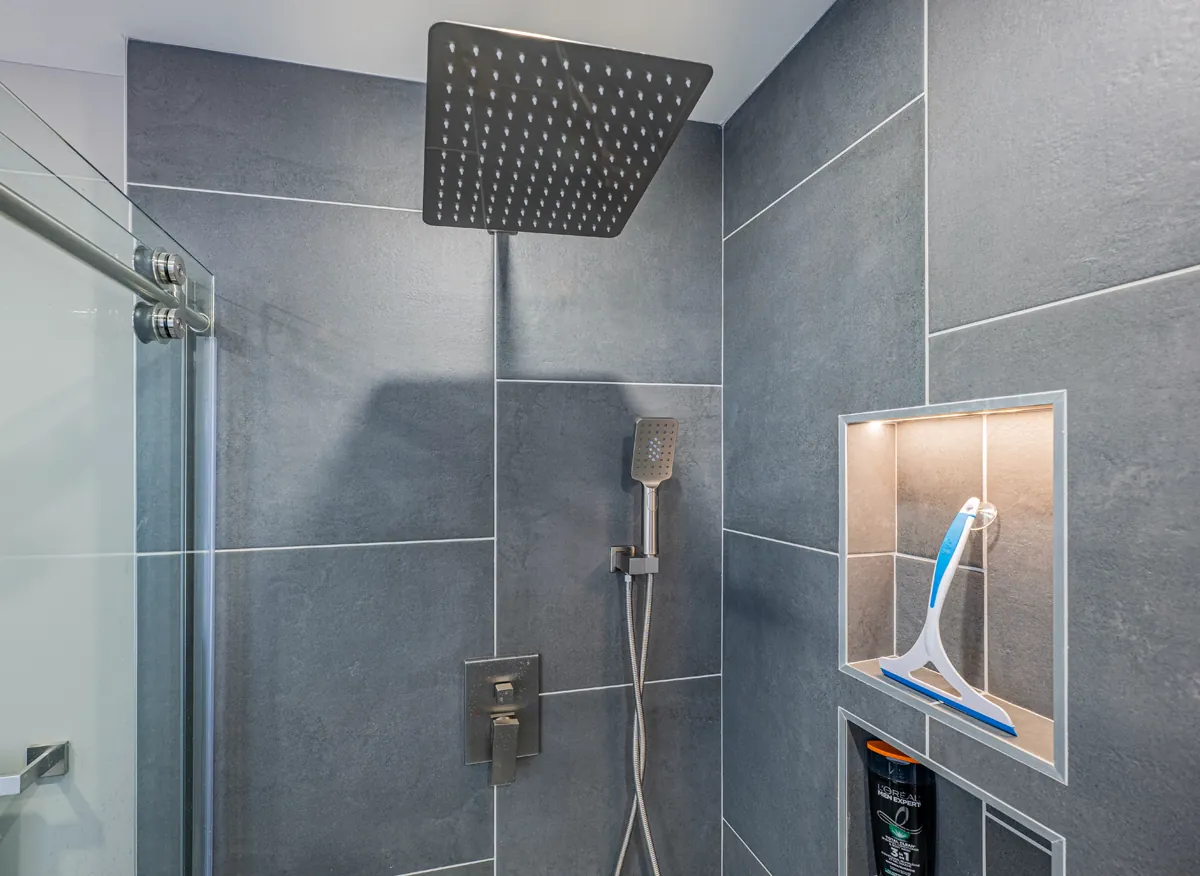 Grey porcelain shower with a square rain head and a lit niche