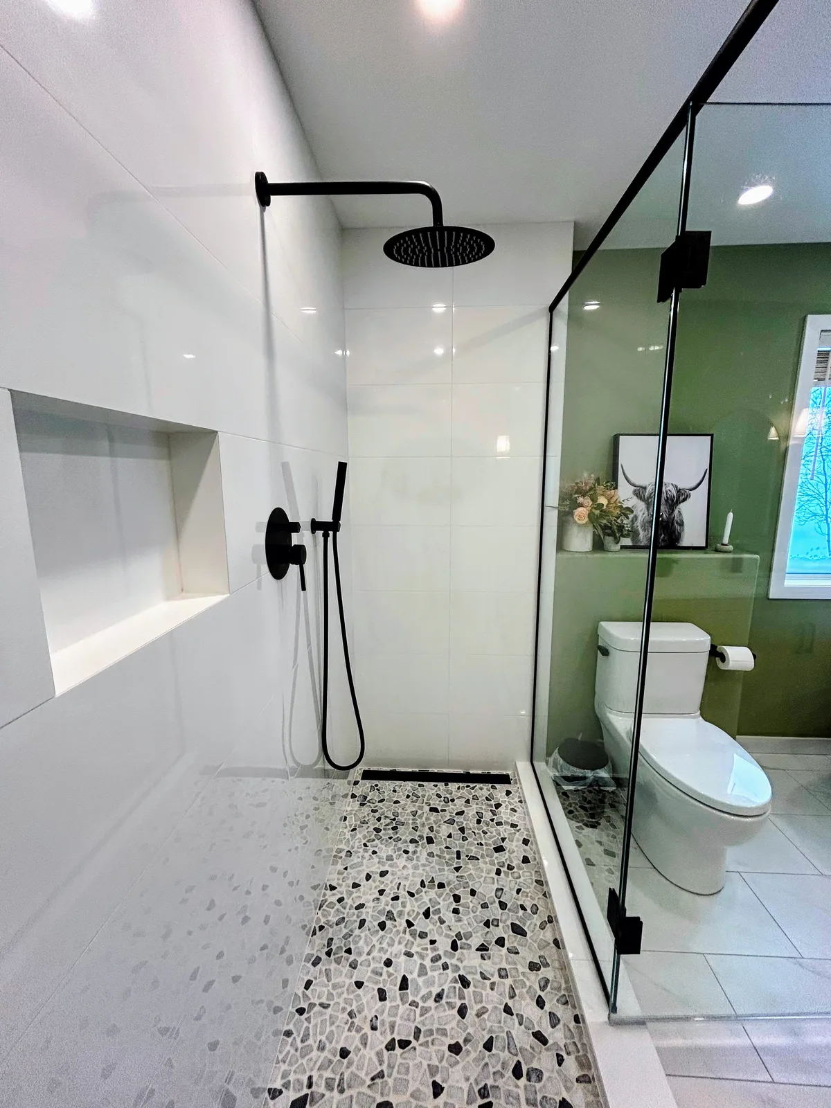 Shower niche and black fittings above a river-stone floor