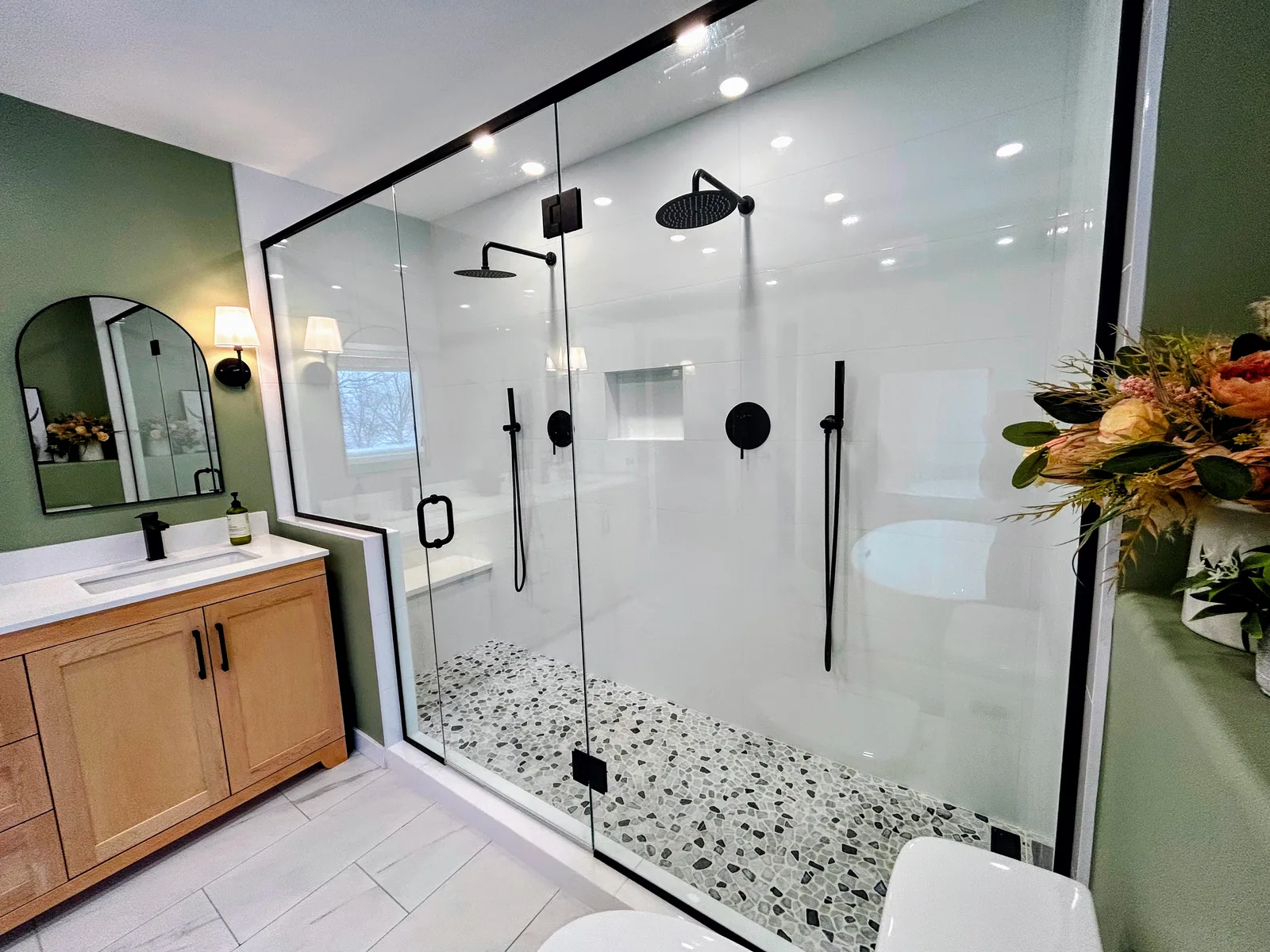 Walk-in shower in full, bench and pebble floor behind frameless glass