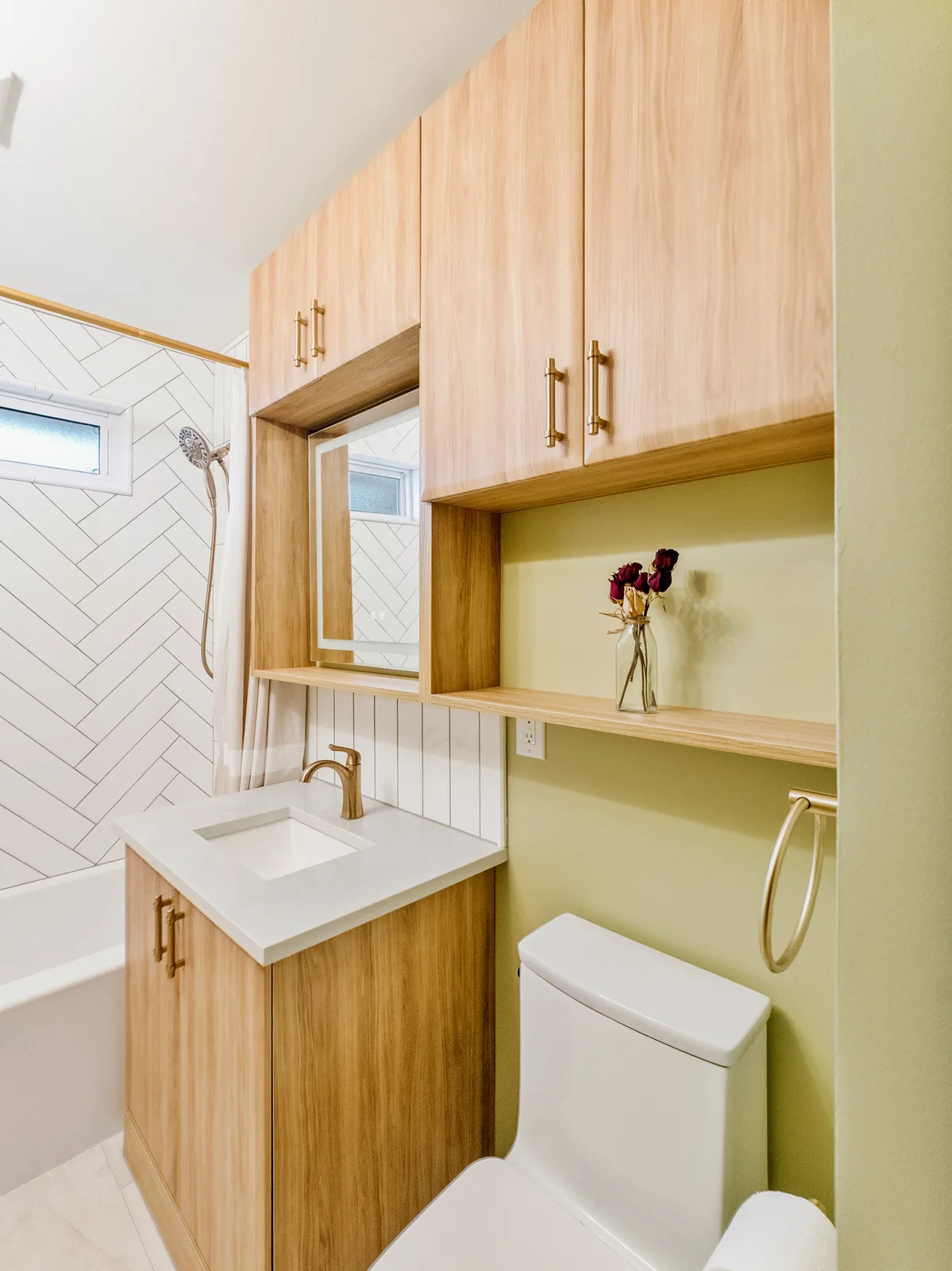 Oak cabinetry and open shelf above the toilet, tub beyond
