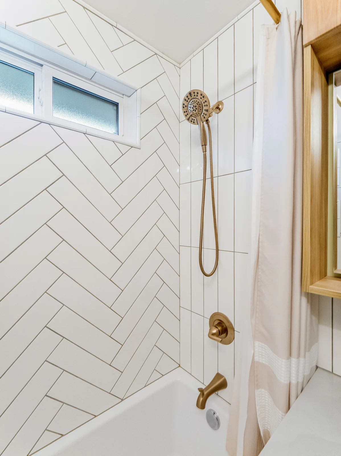 Shower head and tub filler in brass against the tiled surround