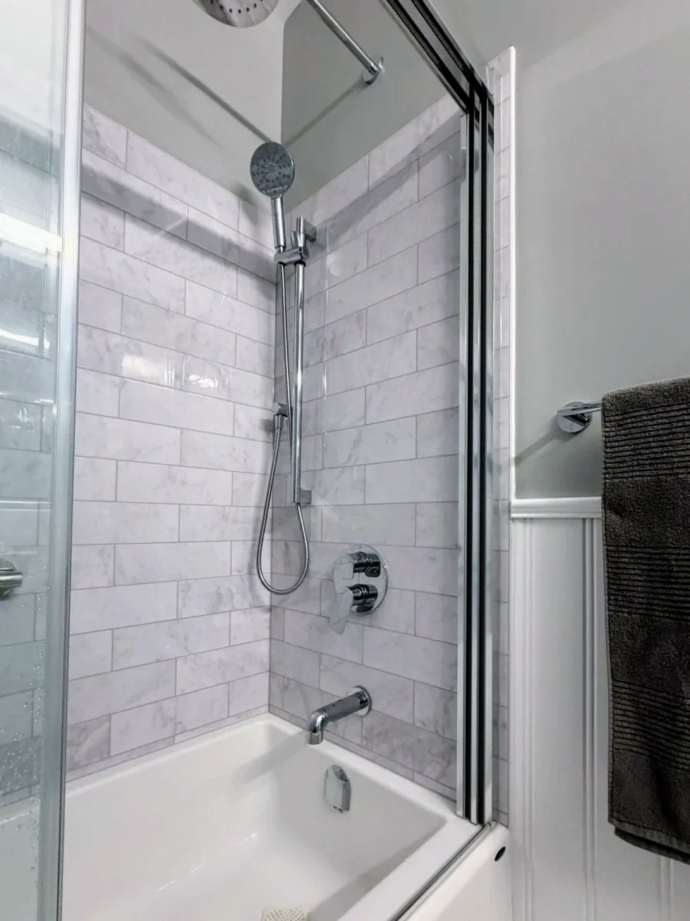 The shower from the doorway, towel bar on the beadboard beside it