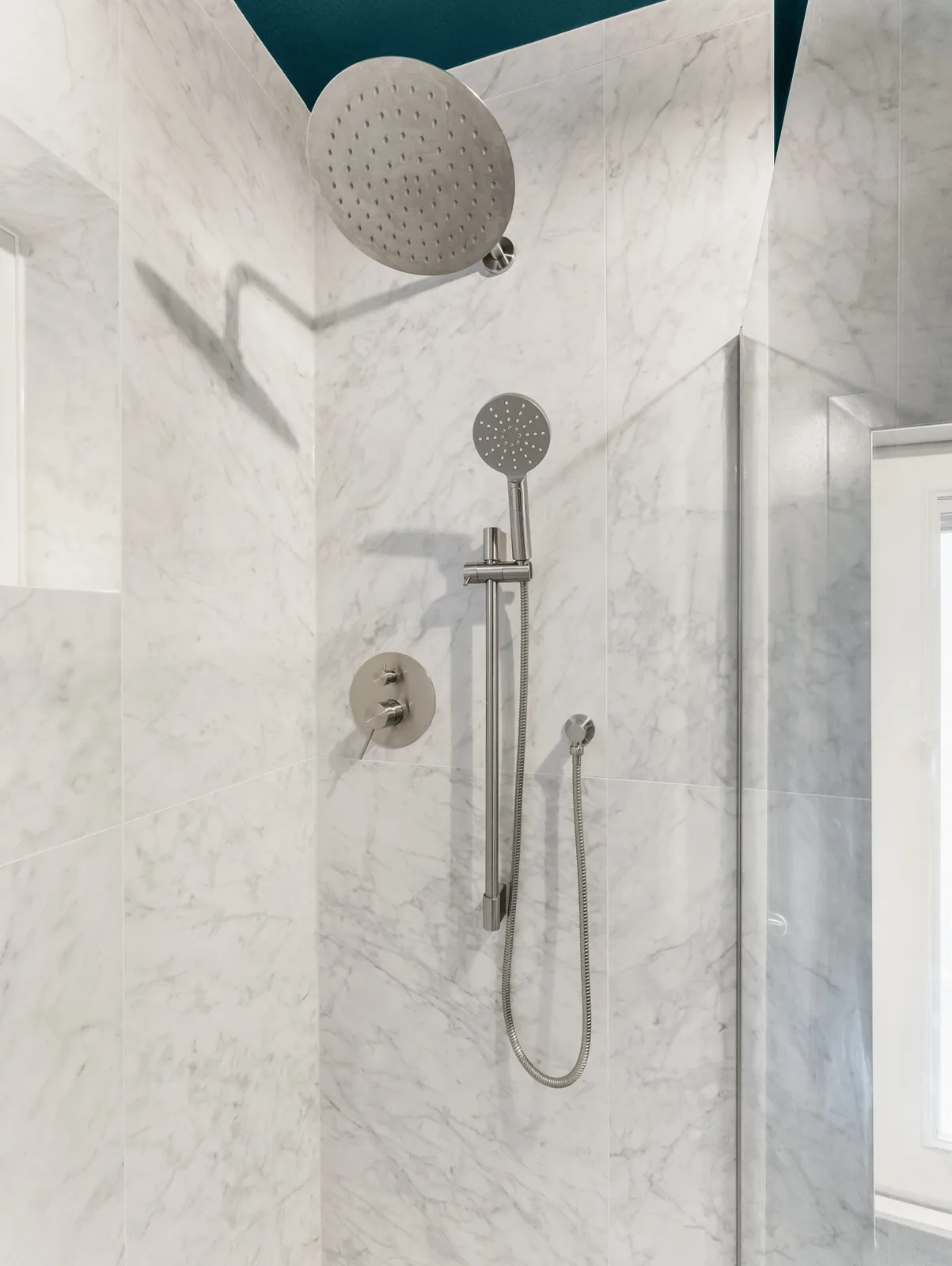 Rain head and hand shower against the veined tile