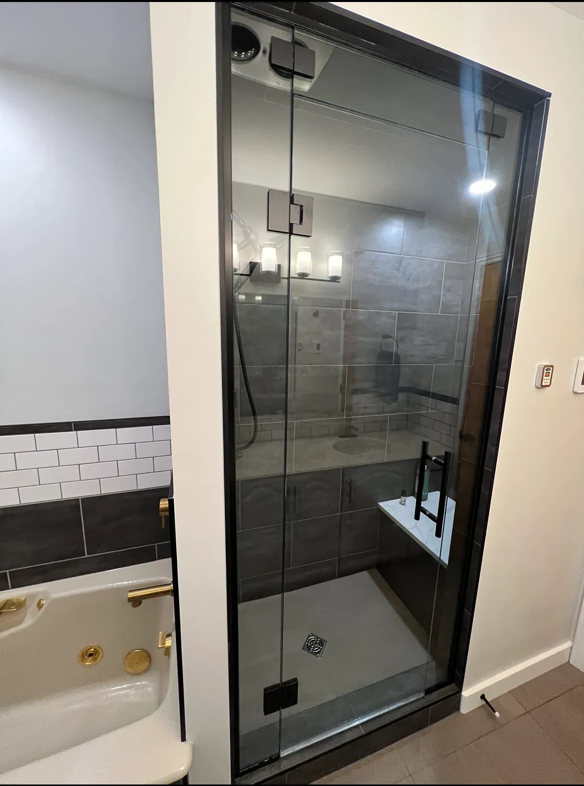 The black-framed shower beside the re-trimmed tub
