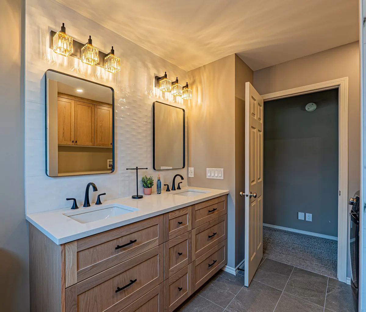 Main bathroom with a light-oak double vanity under two black-framed mirrors, glass light bars above