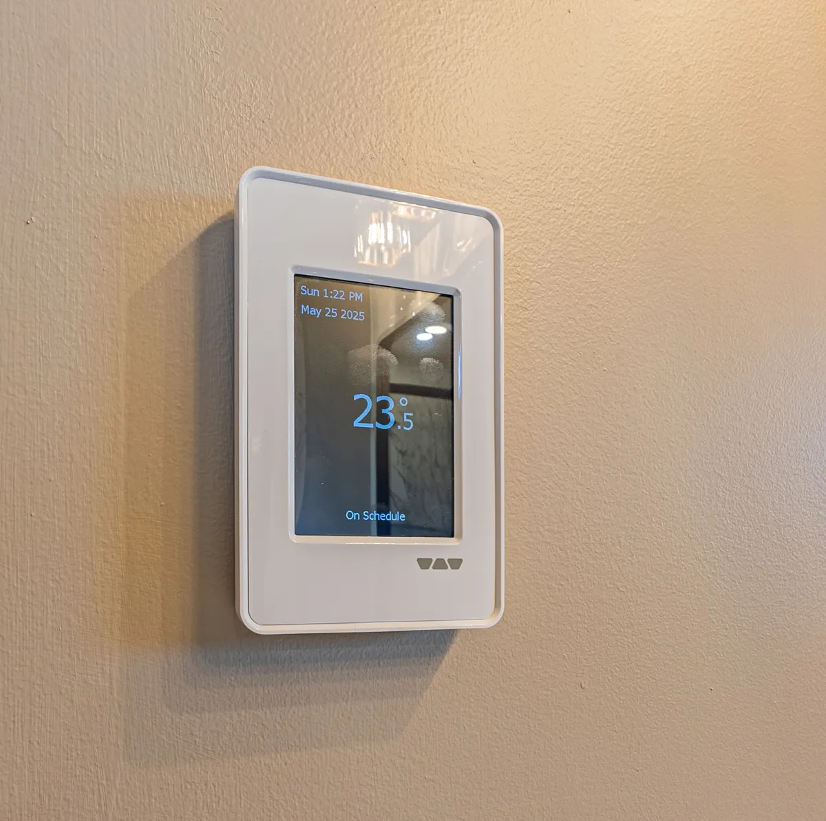 A touchscreen thermostat on the ensuite wall