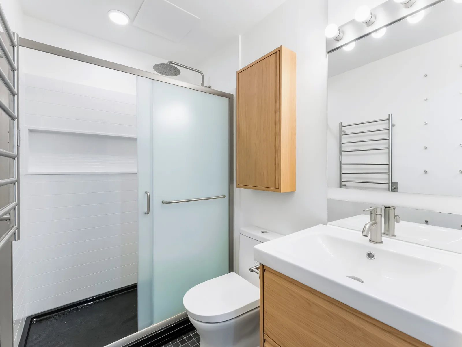 Condo bathroom with an oak vanity, white basin and a frosted-glass shower slider