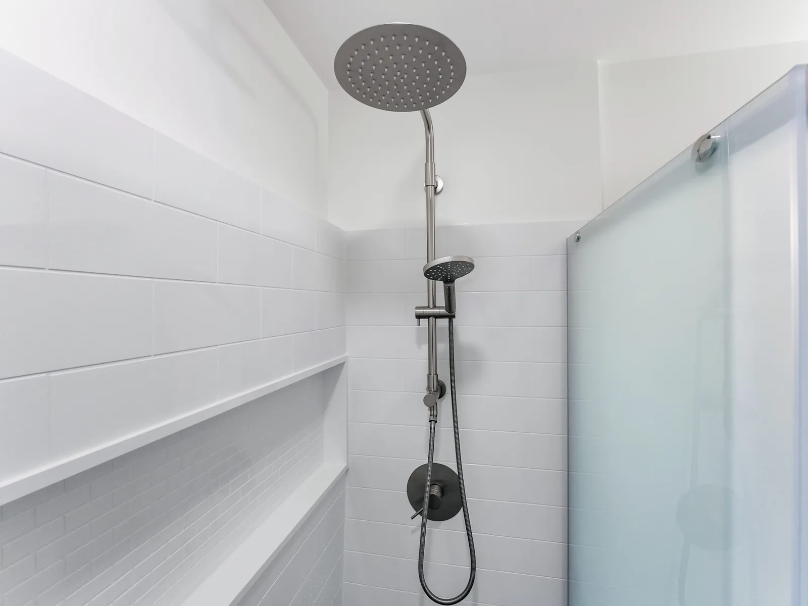 Inside the shower — rain head and hand shower on a white panelled surround