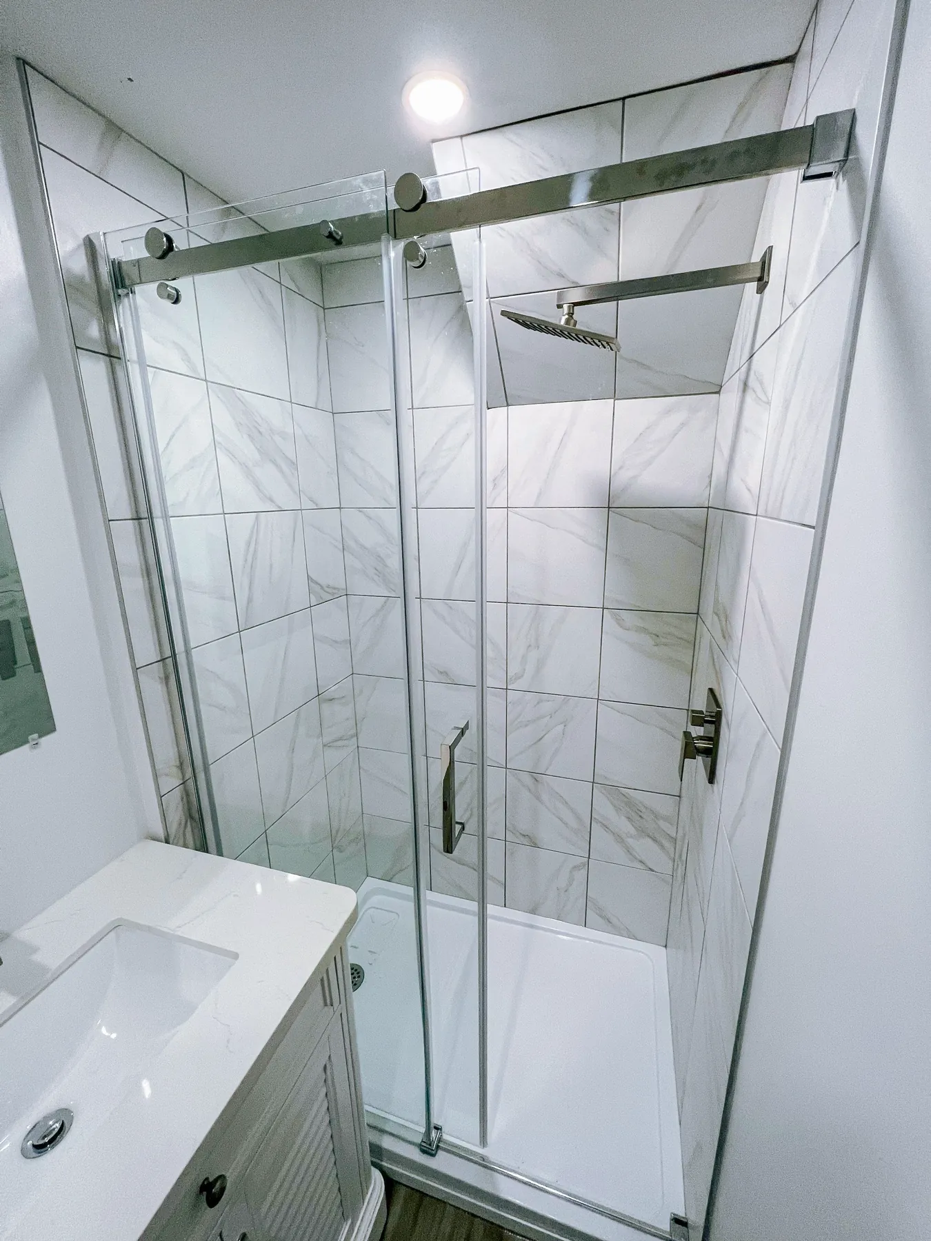 The tiled shower behind its sliding glass door