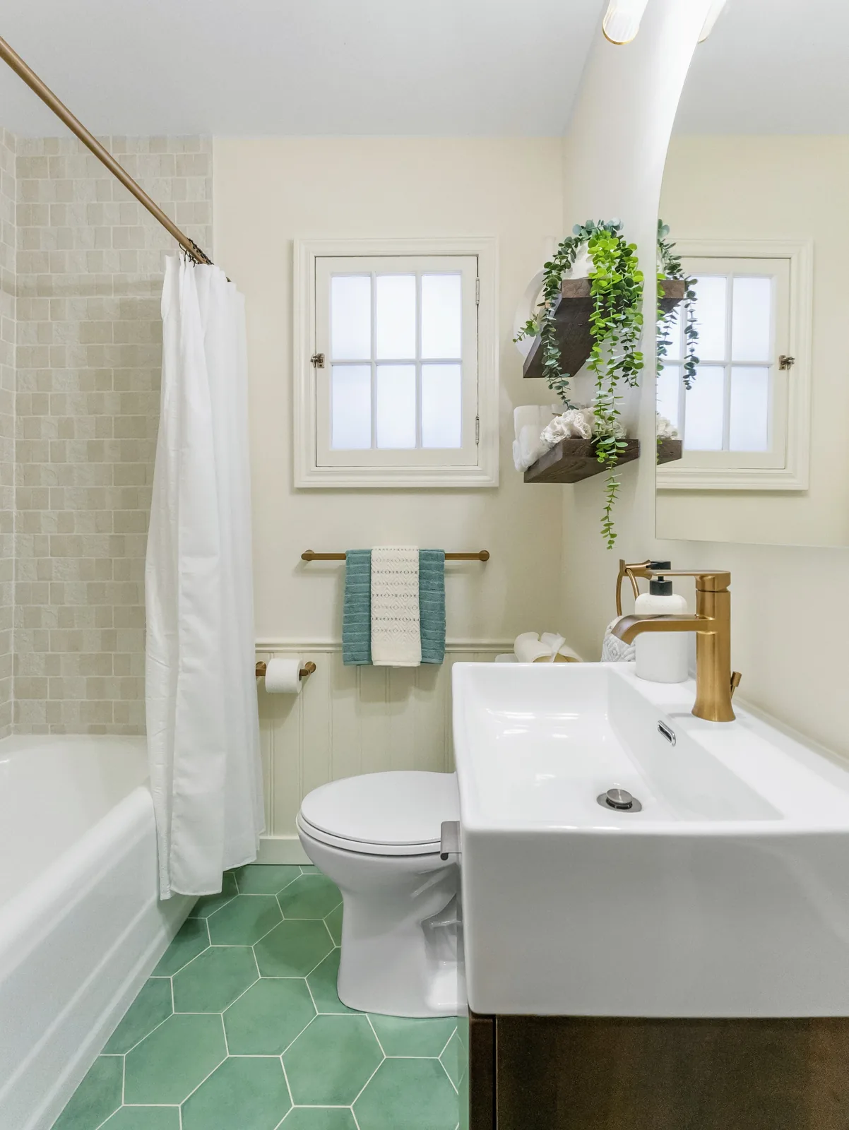 The room from the tub end, window over the vanity and green hex tile underfoot