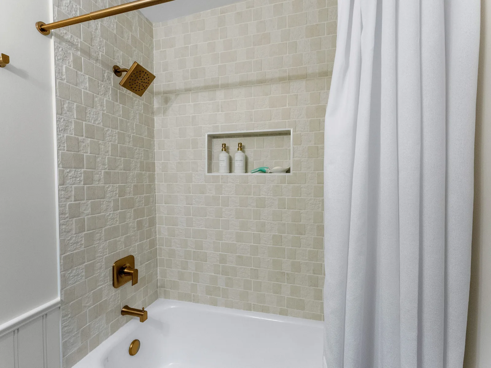 The tub surround in full, niche stocked and curtain drawn back