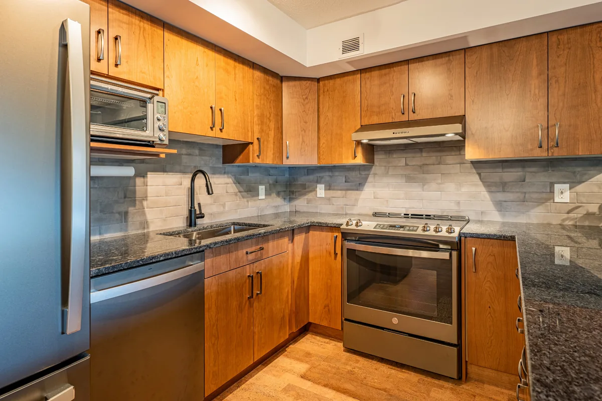 Condo kitchen in cherry cabinetry with granite counters and stainless appliances