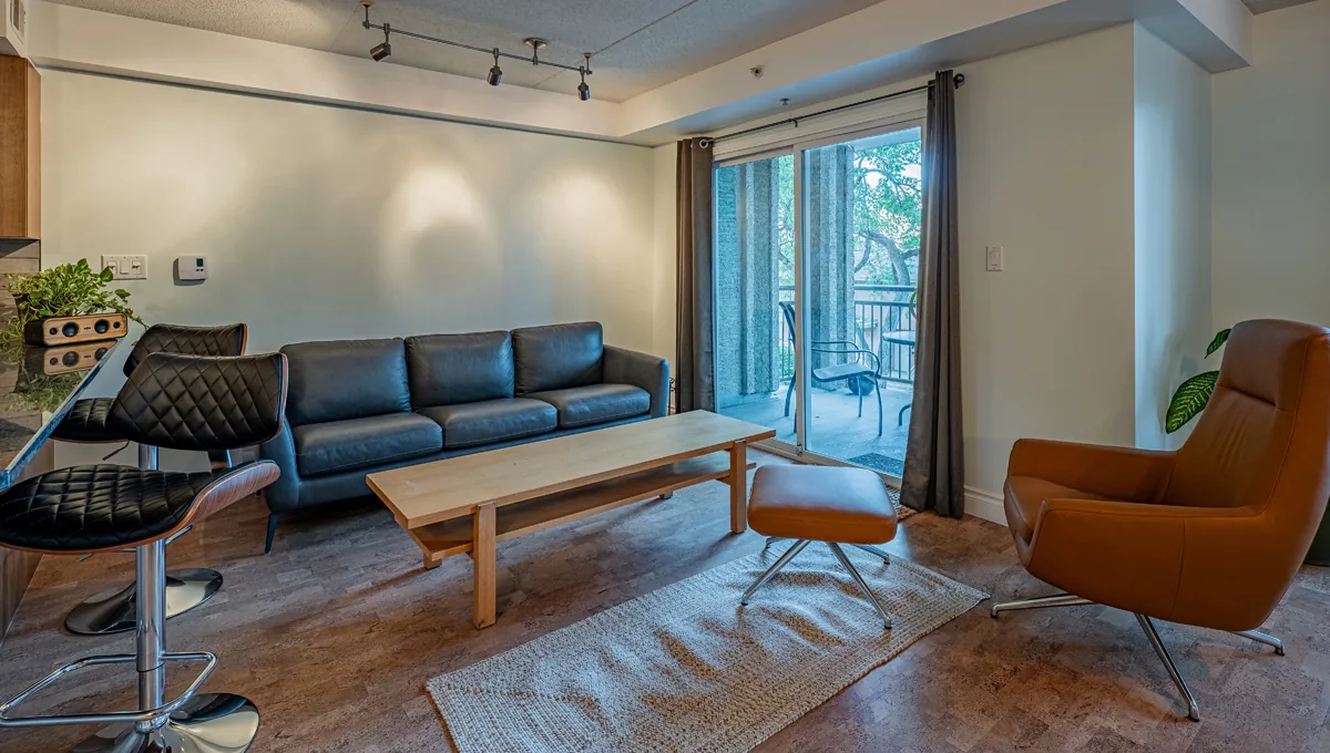 Living room with track lighting and a window wall onto the trees