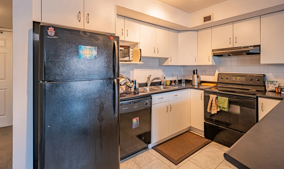 Before: the white kitchen with a black fridge and range