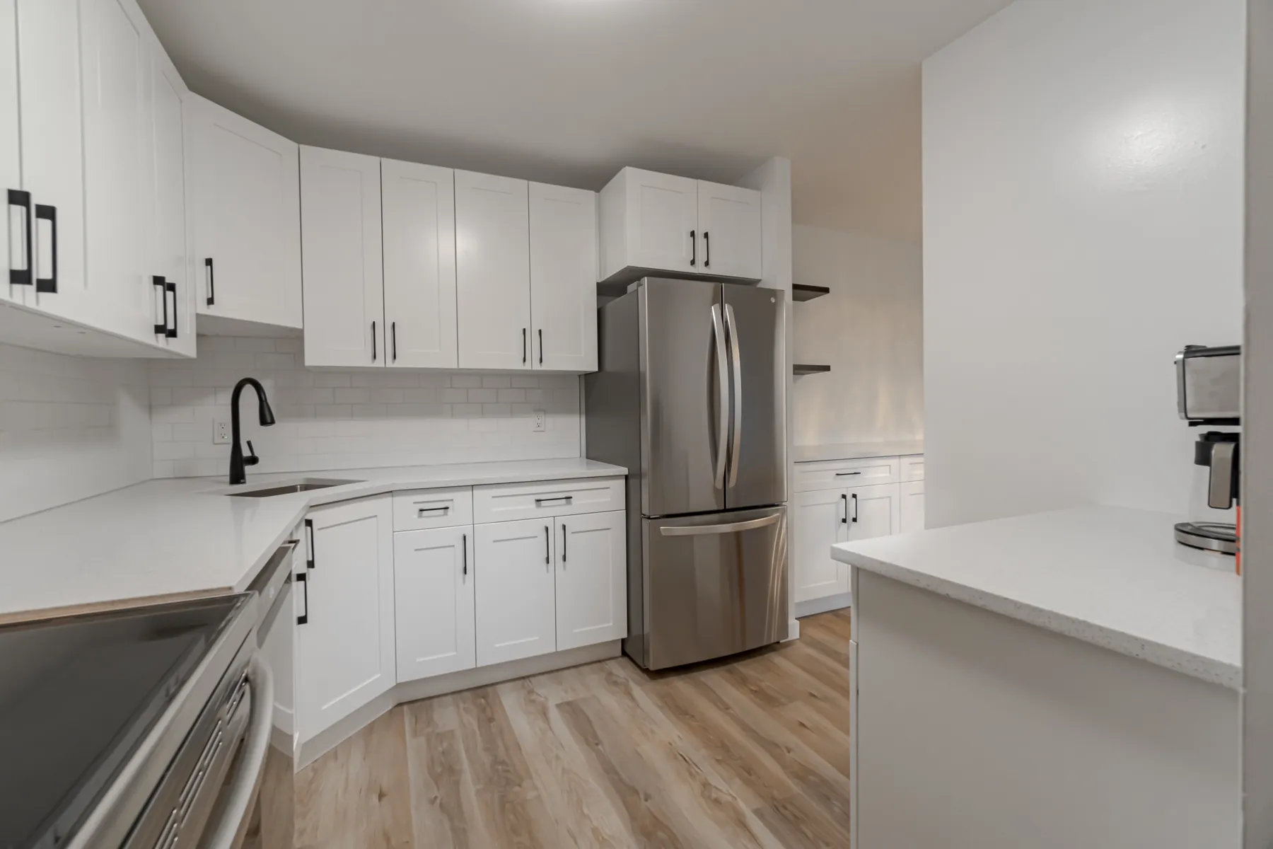 Condo kitchen in white shaker cabinetry with stainless appliances and a black tap