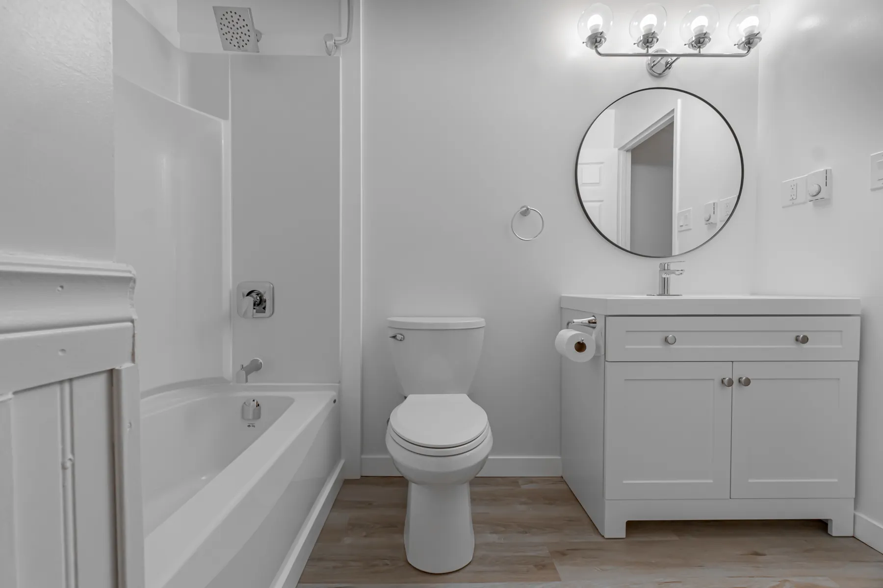 Refitted condo bathroom with a round black mirror and a new vanity