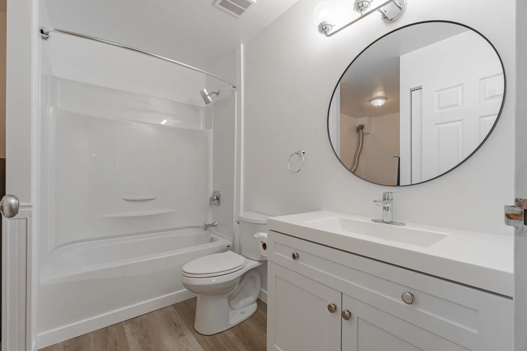 The second bathroom, tub and shower under a round mirror