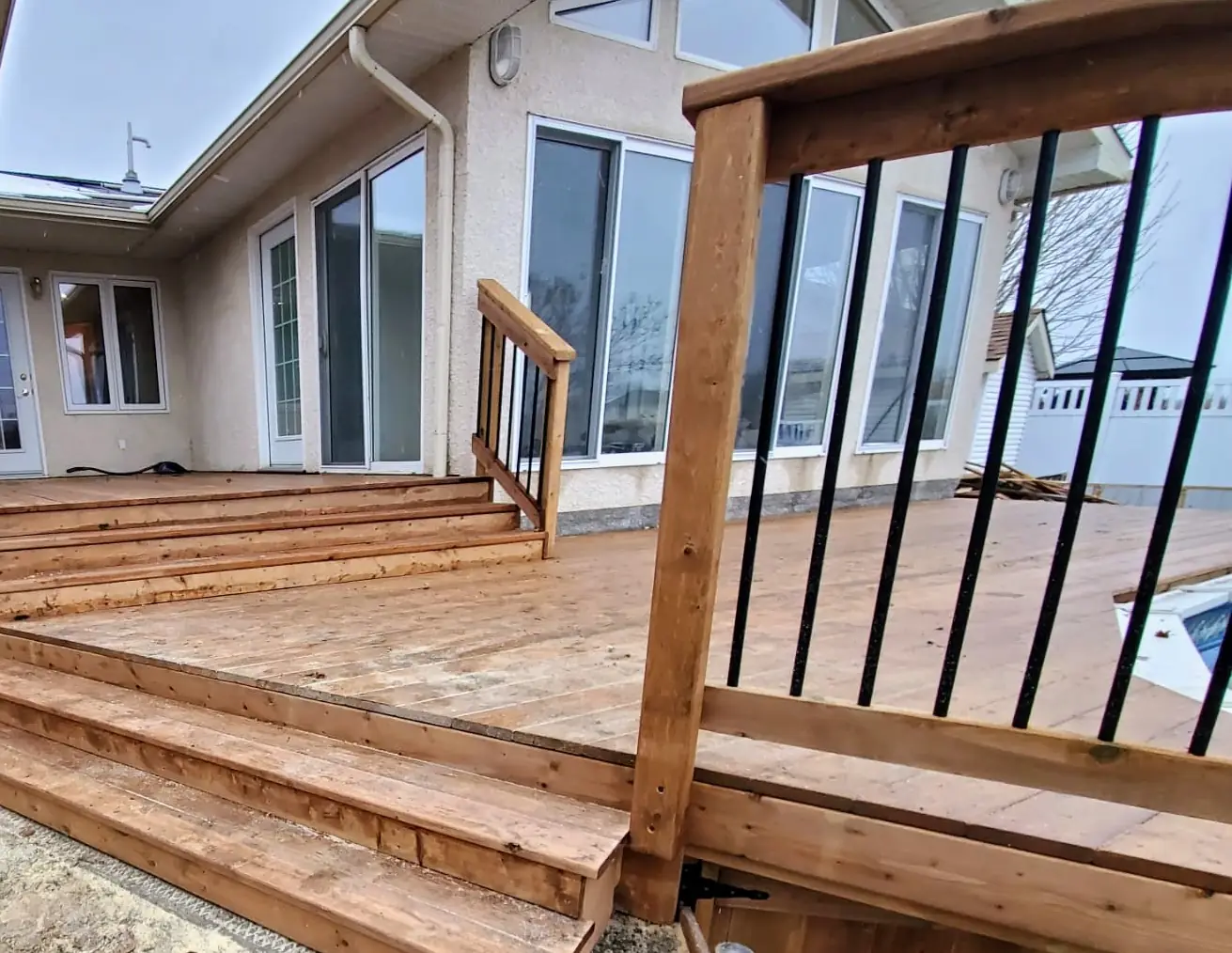 Cedar deck and the broad steps up to the house door, black spindle railing alongside