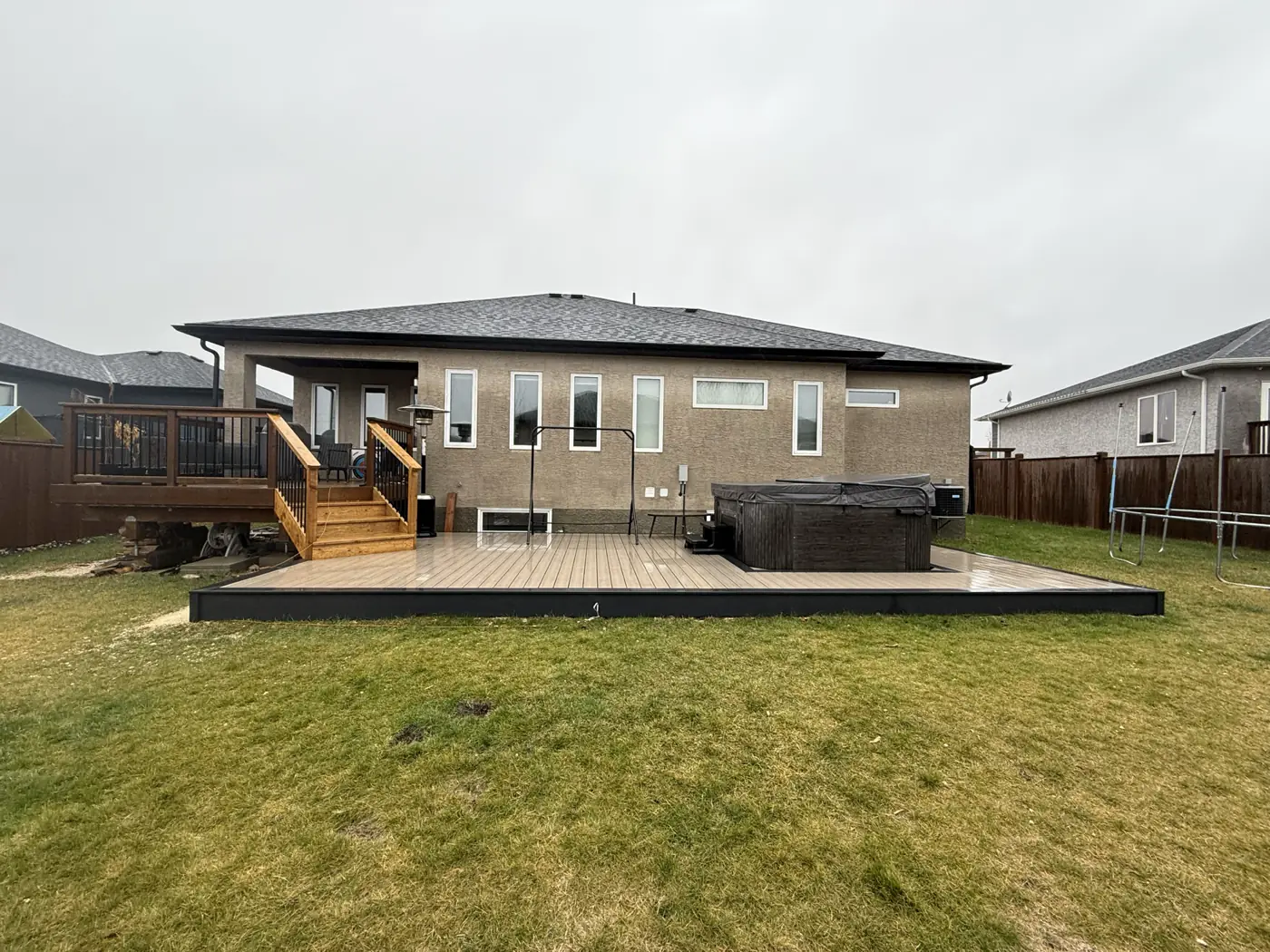 Low composite deck built around a hot tub, trimmed in black fascia