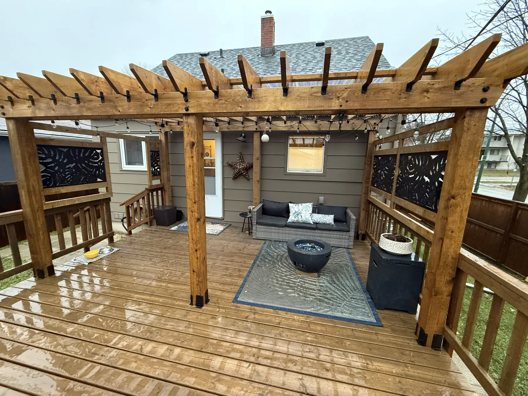 Cedar deck under a pergola, with laser-cut privacy screens and a seating area
