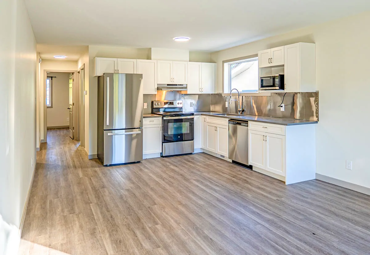 New kitchen in white shaker cabinetry with stainless appliances and a stainless backsplash