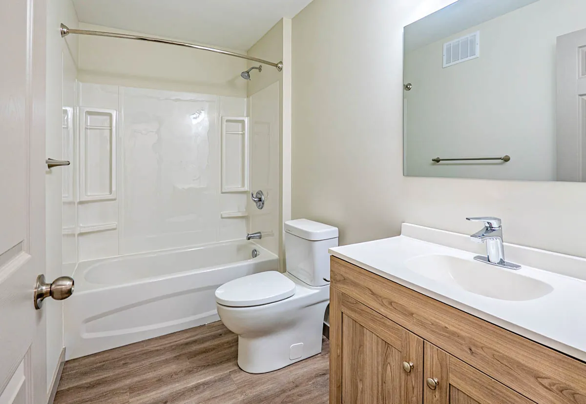 Bathroom with a tub-shower, wood-front vanity and a wide mirror