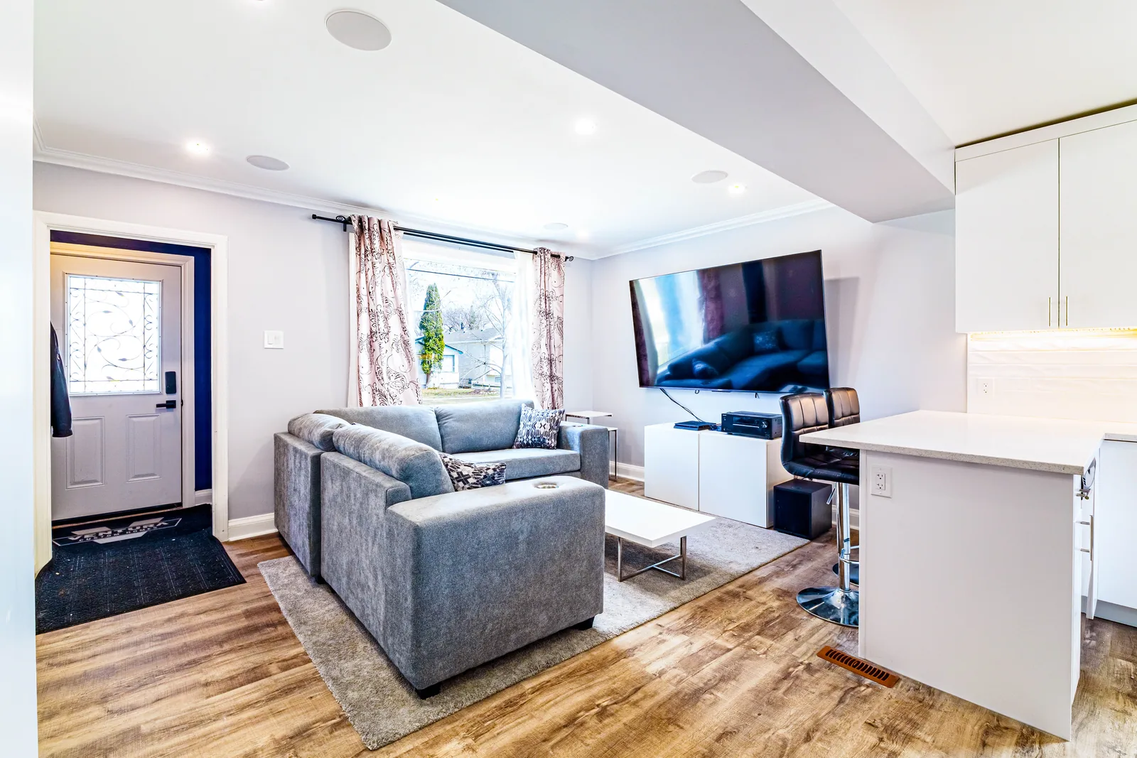 Kitchen opening straight onto the living room, island seating between them