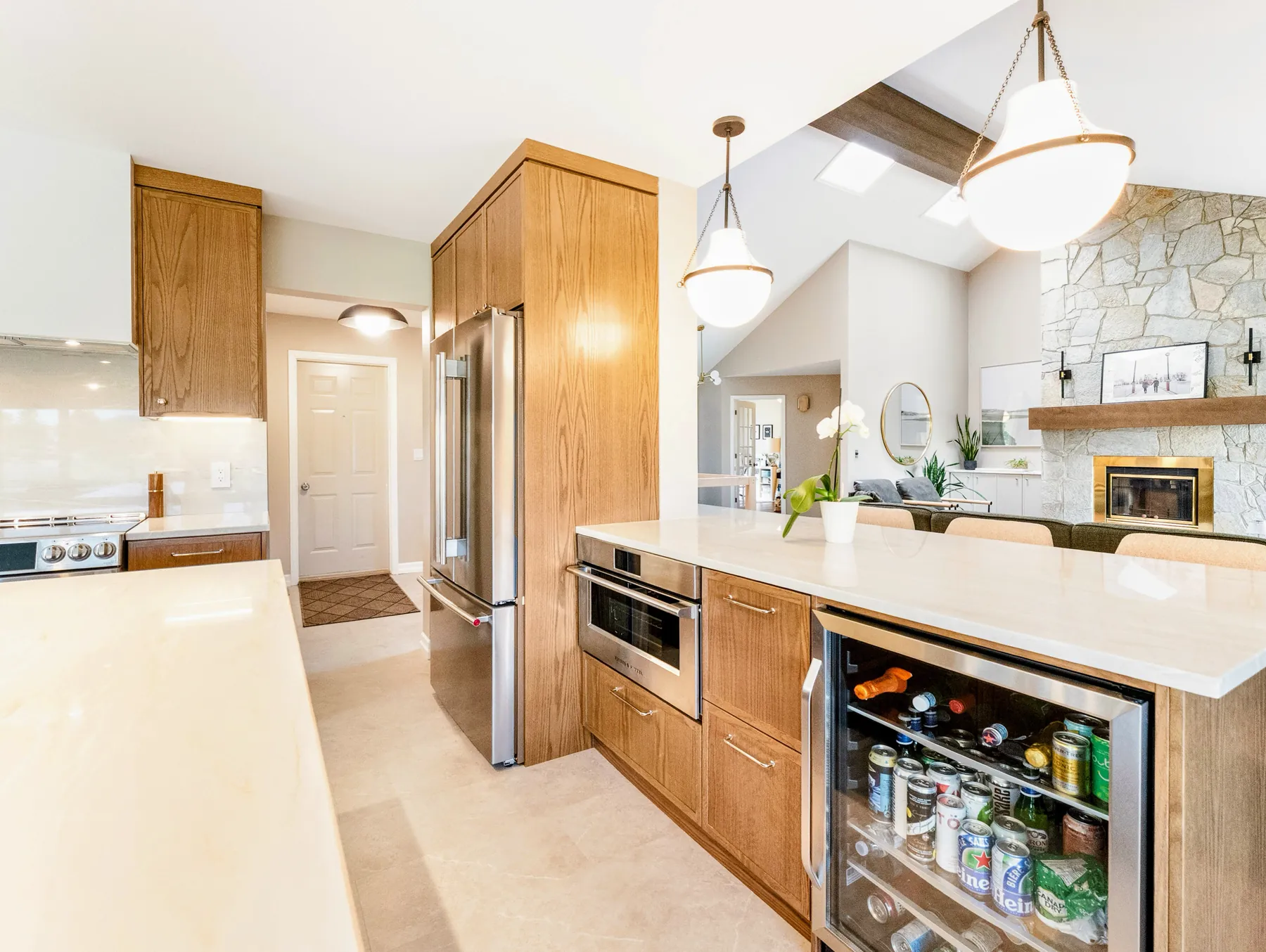 The kitchen side of the bar, with a beverage fridge built in, looking through to the stone fireplace