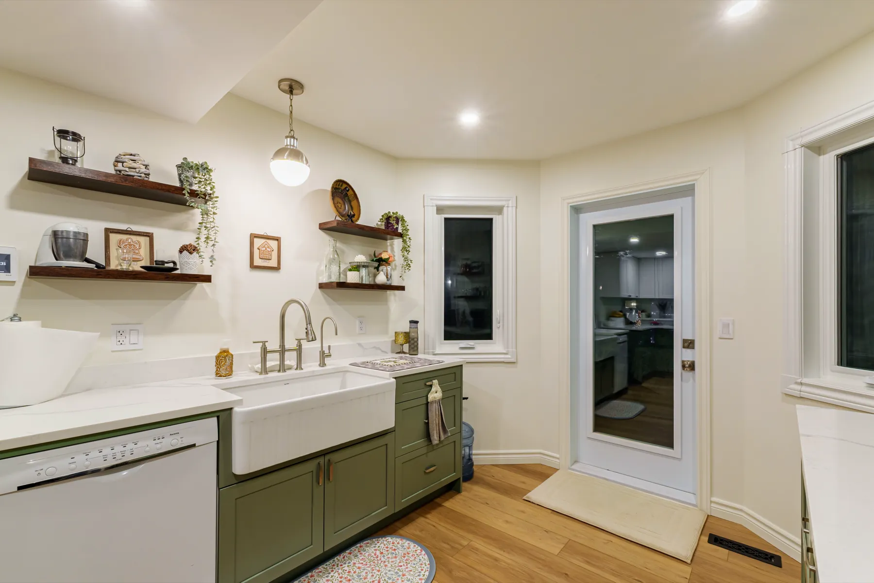 Kitchen with olive-green base cabinets, a white farmhouse sink and walnut open shelving