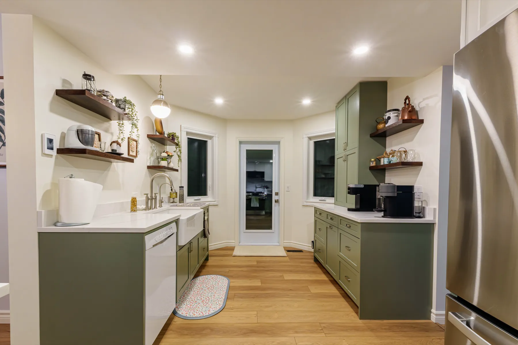 The olive cabinetry run from the far end, fridge and door beyond