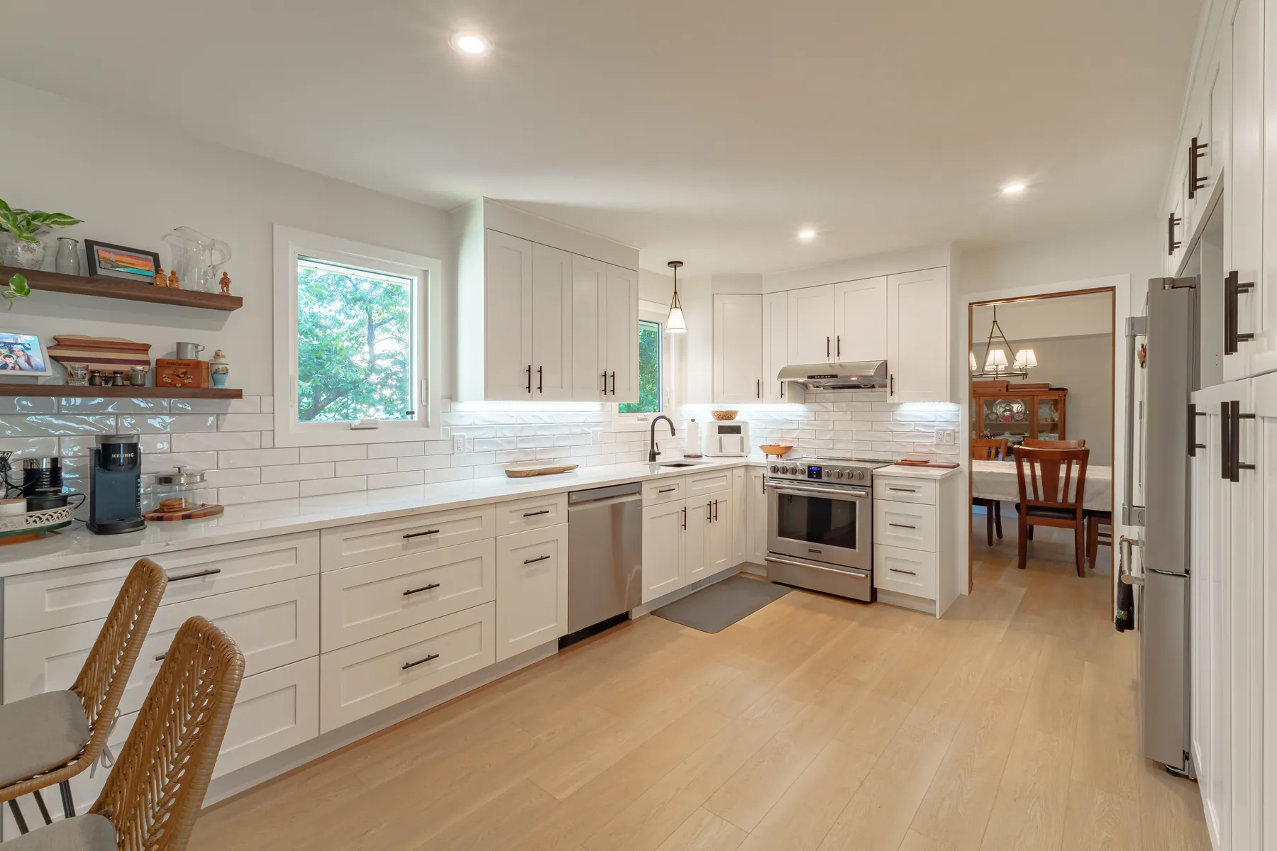 White shaker kitchen with a seated peninsula and walnut open shelving