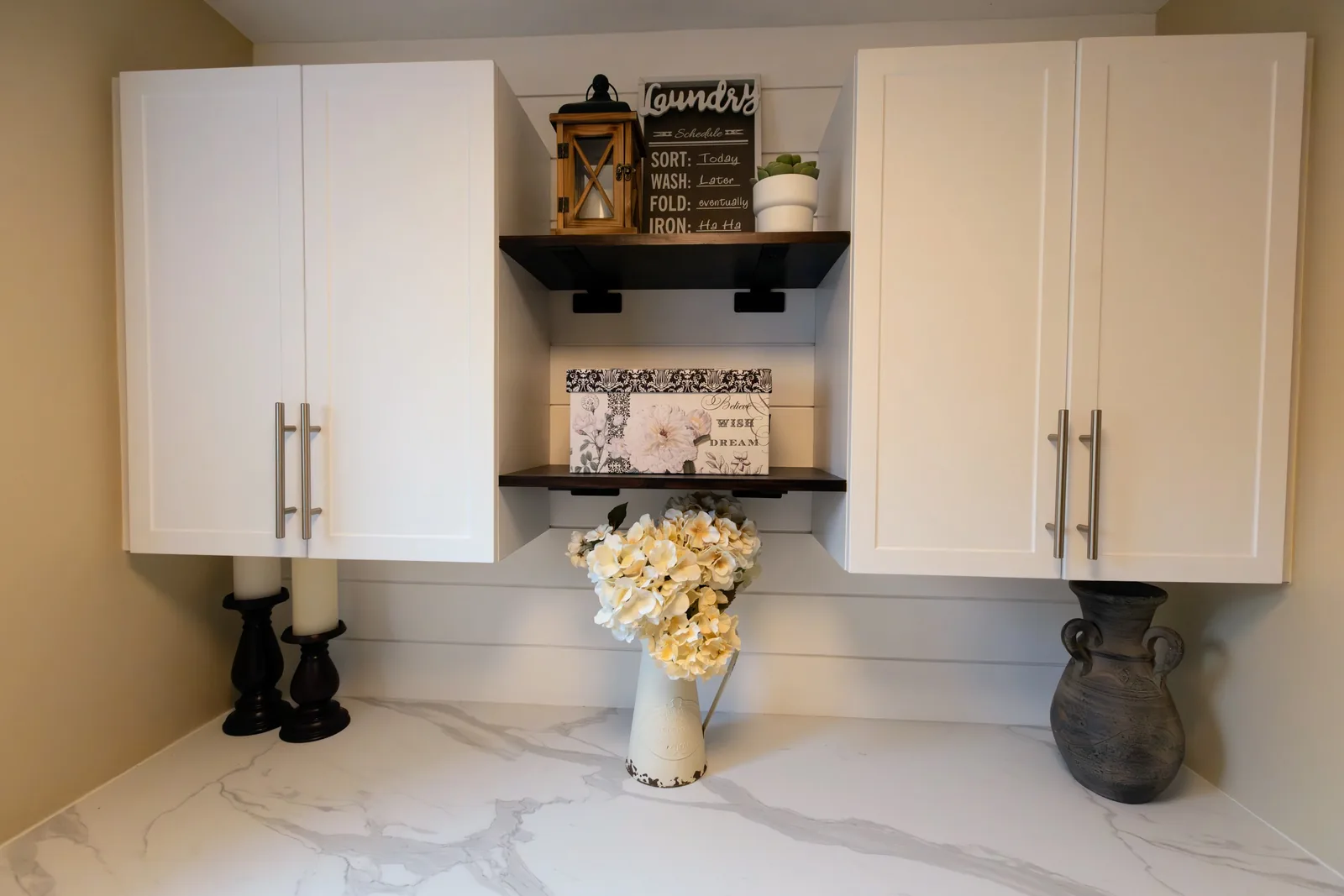 Open dark-wood shelves set between the white uppers, shiplap behind